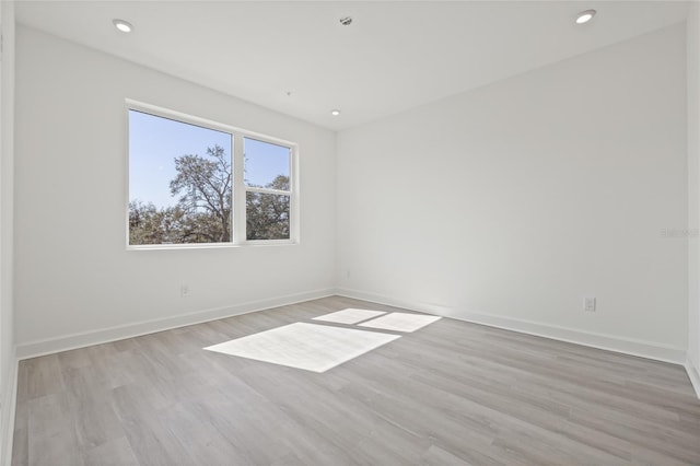 unfurnished room featuring light wood finished floors, baseboards, and recessed lighting