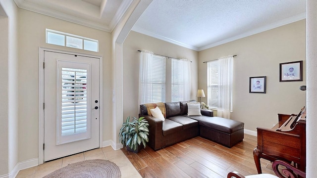 living area featuring a textured ceiling, light wood finished floors, baseboards, and crown molding