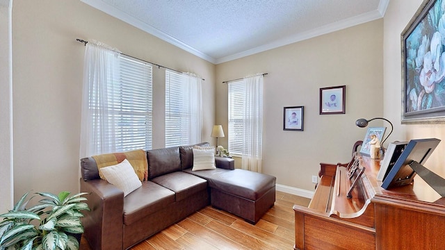 living room featuring light wood finished floors, baseboards, ornamental molding, and a textured ceiling