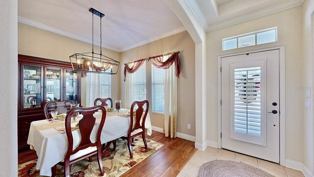 dining room featuring baseboards, light wood finished floors, a notable chandelier, and crown molding