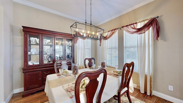 dining space featuring ornamental molding, an inviting chandelier, baseboards, and wood finished floors