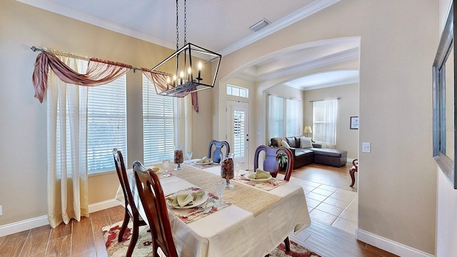 dining area featuring arched walkways, visible vents, ornamental molding, wood finished floors, and baseboards