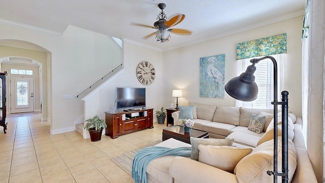 living area featuring light tile patterned floors, arched walkways, a ceiling fan, stairs, and crown molding