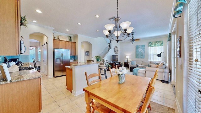 dining space with arched walkways, crown molding, a notable chandelier, visible vents, and light tile patterned flooring