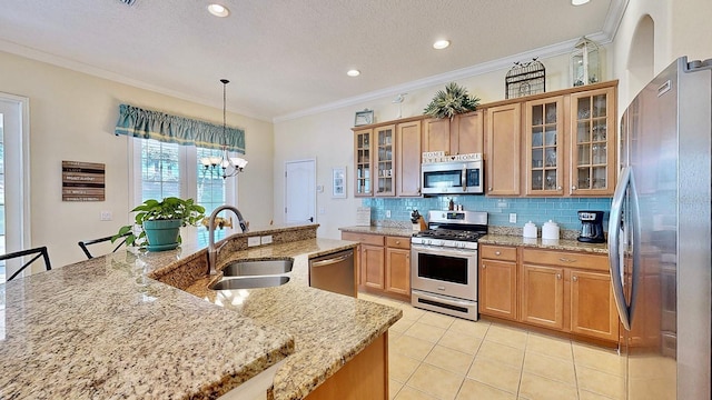 kitchen featuring hanging light fixtures, appliances with stainless steel finishes, glass insert cabinets, a sink, and light stone countertops