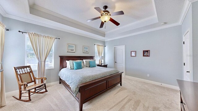 bedroom with ornamental molding, baseboards, a raised ceiling, and light colored carpet