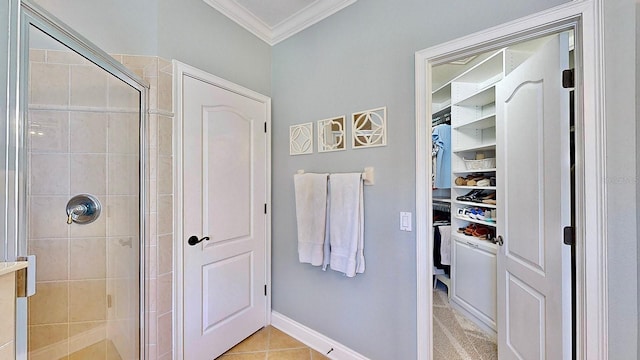 full bathroom featuring baseboards, tile patterned floors, a spacious closet, crown molding, and a shower stall