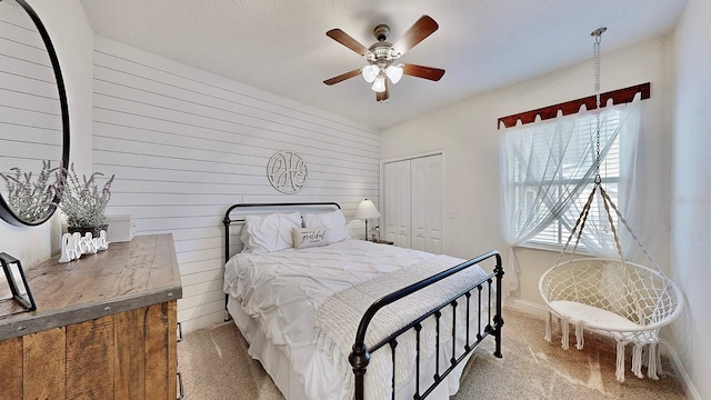 carpeted bedroom featuring a closet, wood walls, baseboards, and ceiling fan