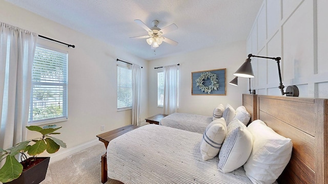 bedroom with light carpet, multiple windows, baseboards, and a textured ceiling