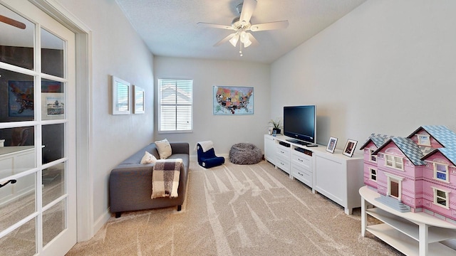 sitting room with ceiling fan, a textured ceiling, and light colored carpet