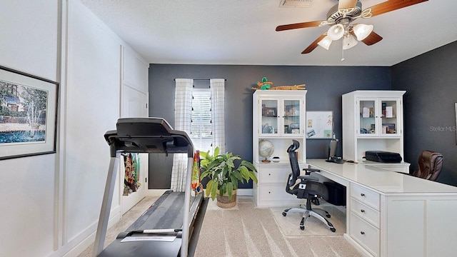 home office with light carpet, visible vents, a ceiling fan, and a textured ceiling