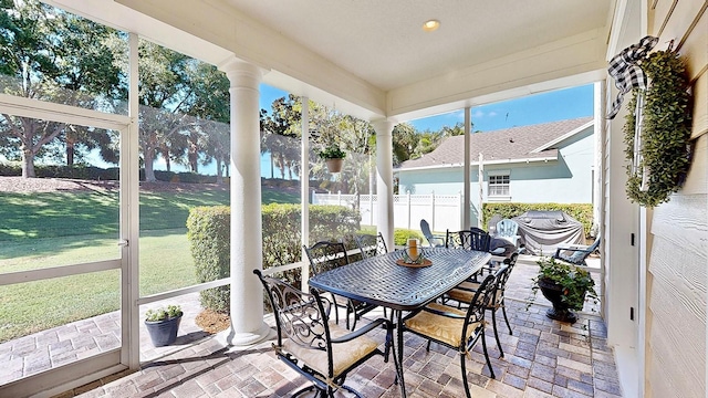 sunroom featuring a water view and ornate columns