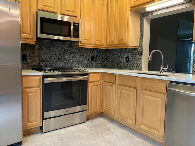 kitchen featuring light countertops, appliances with stainless steel finishes, a sink, and tasteful backsplash