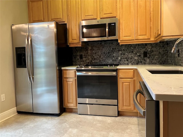 kitchen with appliances with stainless steel finishes, brown cabinetry, a sink, and tasteful backsplash