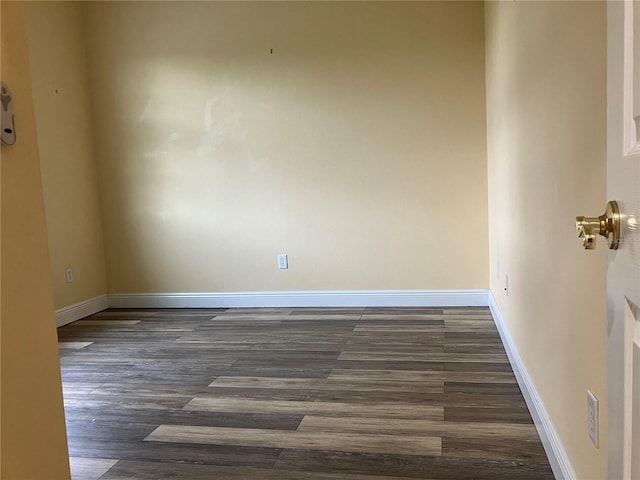 unfurnished room with dark wood-style flooring and baseboards