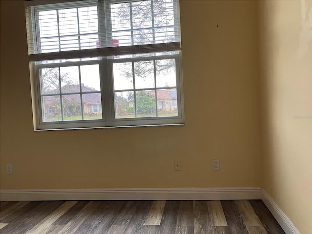 spare room featuring baseboards and wood finished floors