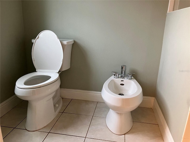 bathroom featuring toilet, tile patterned flooring, a bidet, and baseboards