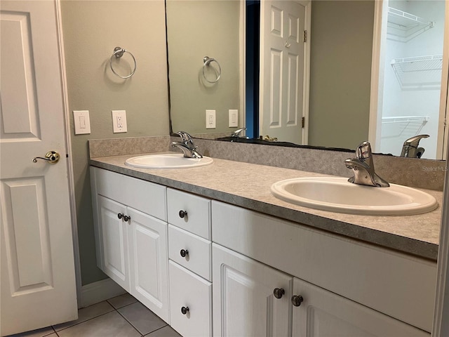 bathroom with tile patterned flooring, a sink, a spacious closet, and double vanity