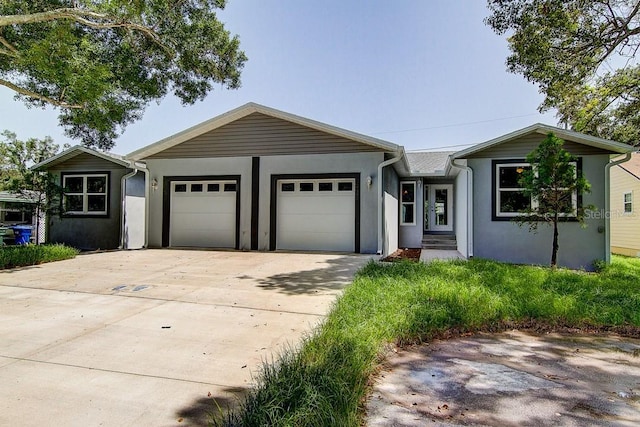 single story home featuring an attached garage, concrete driveway, and stucco siding