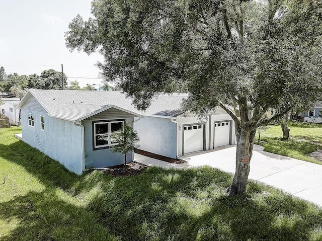 view of front of house featuring a front yard, driveway, an attached garage, and stucco siding