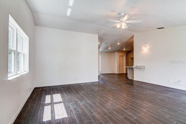 empty room with wood tiled floor, visible vents, vaulted ceiling, and baseboards