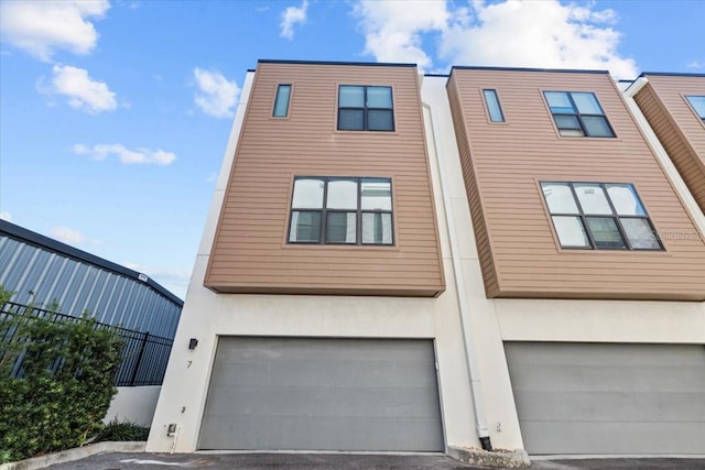 multi unit property with a garage, fence, and stucco siding