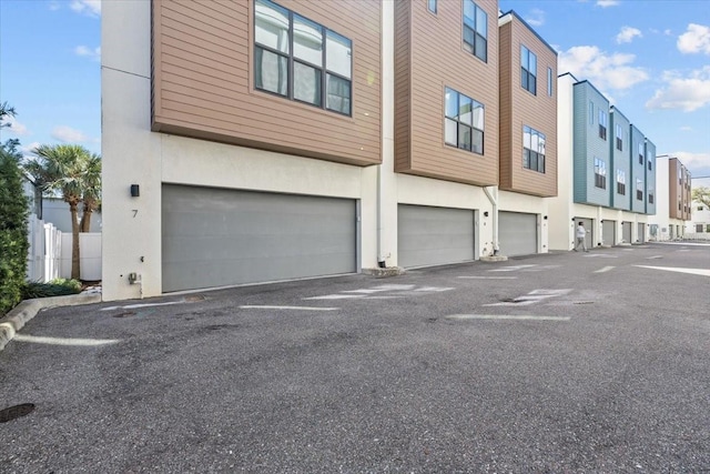 exterior space featuring a garage, driveway, a residential view, and stucco siding