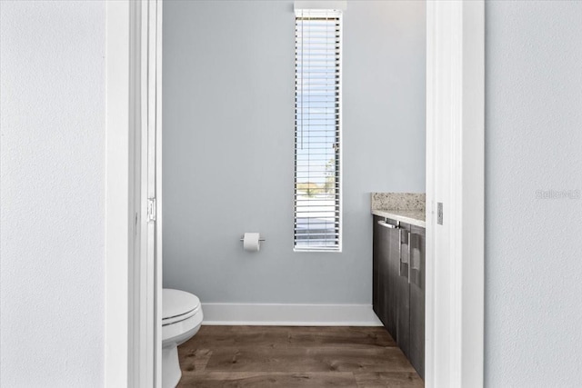 bathroom with toilet, baseboards, wood finished floors, and vanity