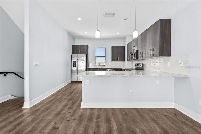 kitchen with dark wood-style flooring, stainless steel appliances, decorative backsplash, dark brown cabinets, and a peninsula