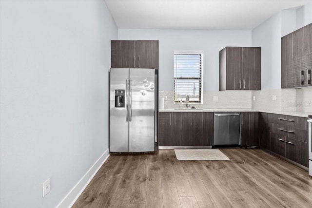 kitchen featuring appliances with stainless steel finishes, a sink, dark brown cabinetry, and decorative backsplash