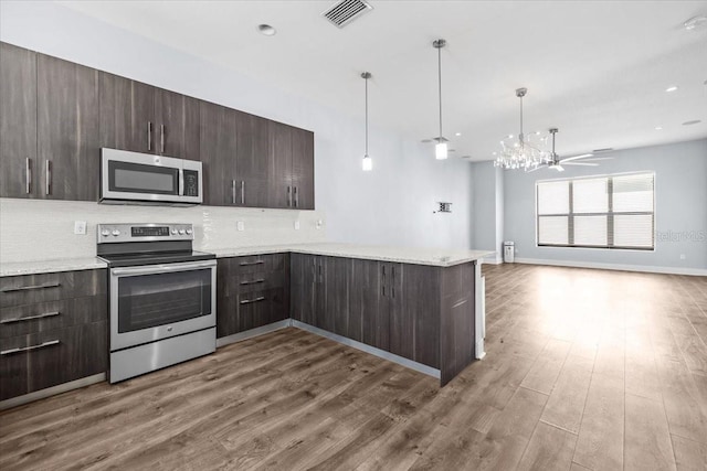 kitchen featuring dark brown cabinetry, stainless steel appliances, wood finished floors, visible vents, and open floor plan