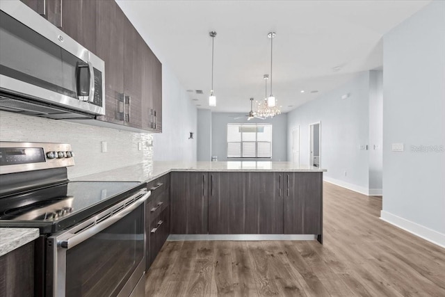 kitchen with stainless steel appliances, a peninsula, dark brown cabinets, and wood finished floors