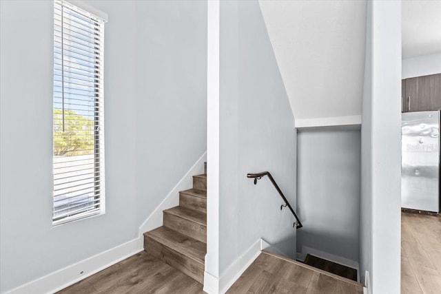 staircase featuring wood finished floors and baseboards