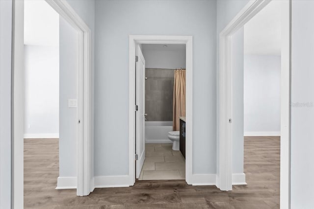 hall with baseboards and wood finished floors