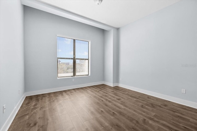 empty room featuring dark wood-type flooring and baseboards