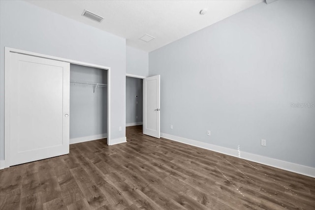 unfurnished bedroom with baseboards, visible vents, dark wood finished floors, and a closet