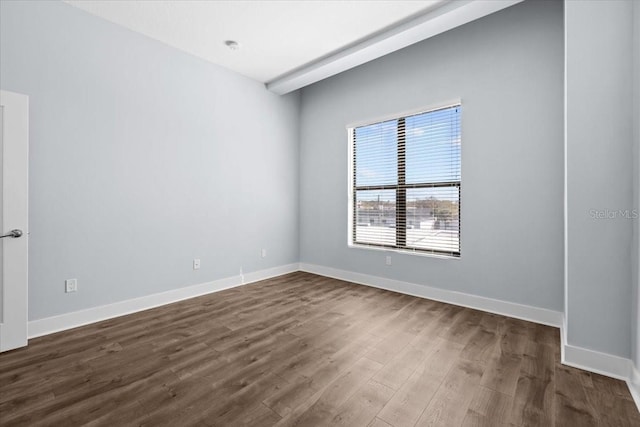 spare room with baseboards and dark wood-style flooring