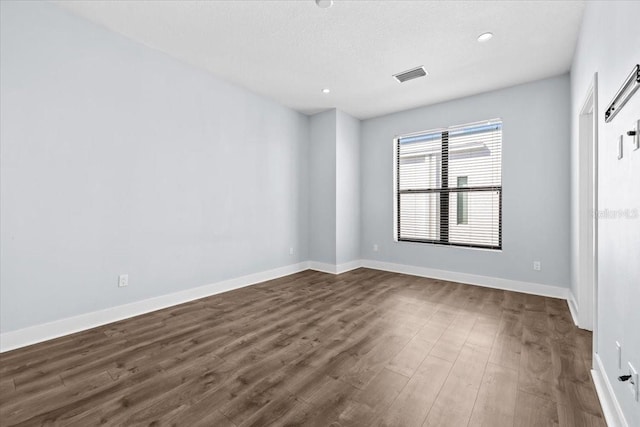 empty room featuring dark wood-type flooring, recessed lighting, visible vents, and baseboards