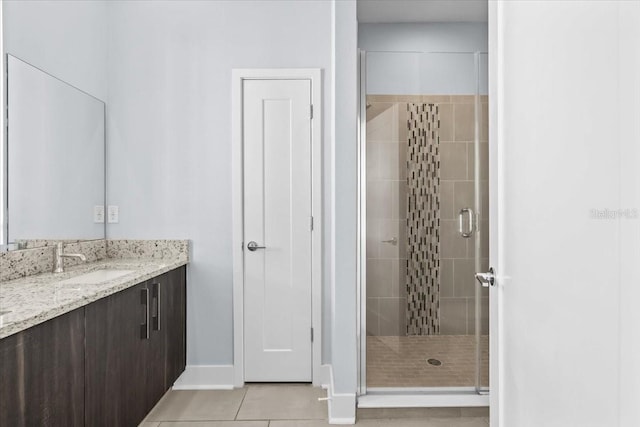 bathroom featuring a stall shower, vanity, baseboards, and tile patterned floors