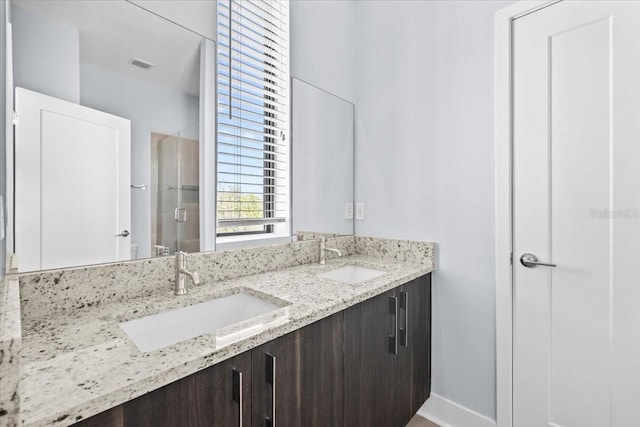 bathroom featuring double vanity, a shower stall, visible vents, and a sink