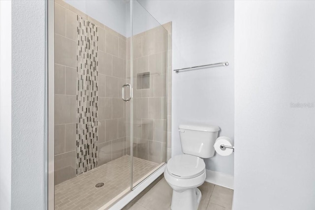 full bath featuring a stall shower, tile patterned flooring, baseboards, and toilet