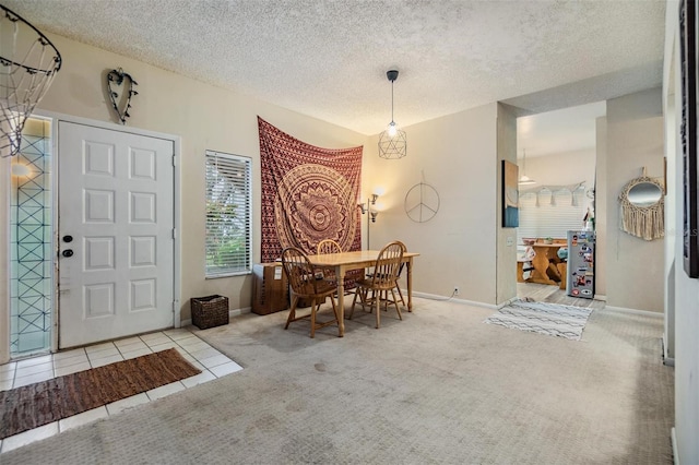 dining room with light carpet, a textured ceiling, baseboards, and light tile patterned floors