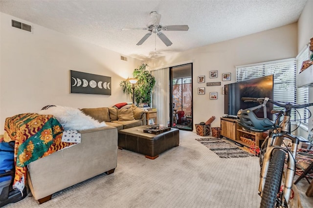 carpeted living room with a ceiling fan, visible vents, and a textured ceiling