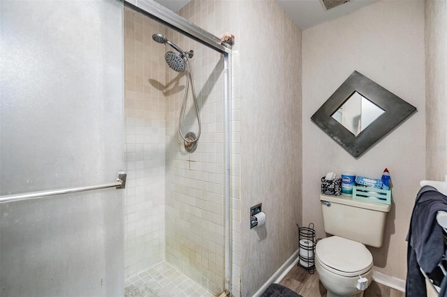 bathroom featuring a stall shower, baseboards, toilet, and wood finished floors