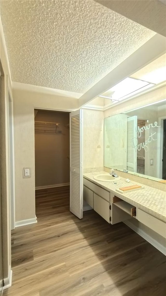 1822 Lake Cypress Dr Unit 1822, Safety Harbor, FL 34695 - bathroom with a closet, a textured ceiling, baseboards, vanity, and wood finished floors