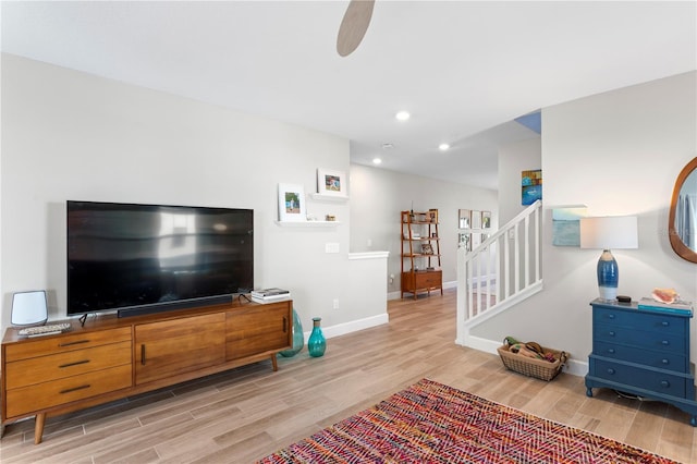 living area with recessed lighting, ceiling fan, wood finished floors, baseboards, and stairs