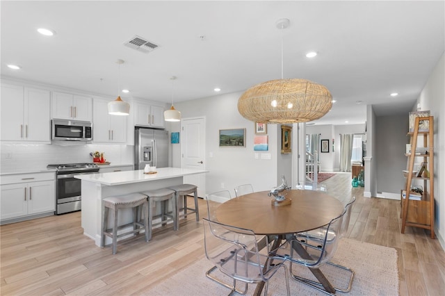 dining room featuring baseboards, light wood finished floors, visible vents, and recessed lighting