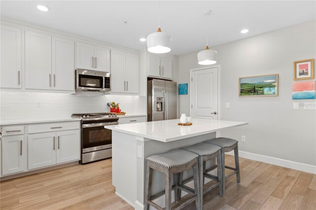 kitchen featuring light wood-style flooring, a kitchen breakfast bar, a center island, stainless steel appliances, and backsplash