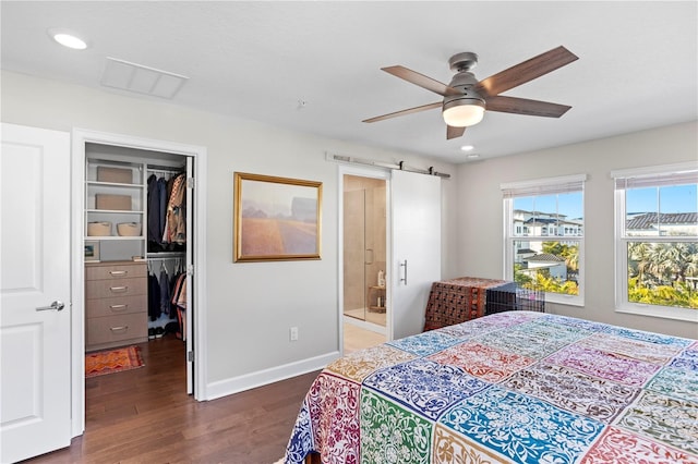 bedroom featuring a barn door, visible vents, dark wood finished floors, a closet, and a walk in closet