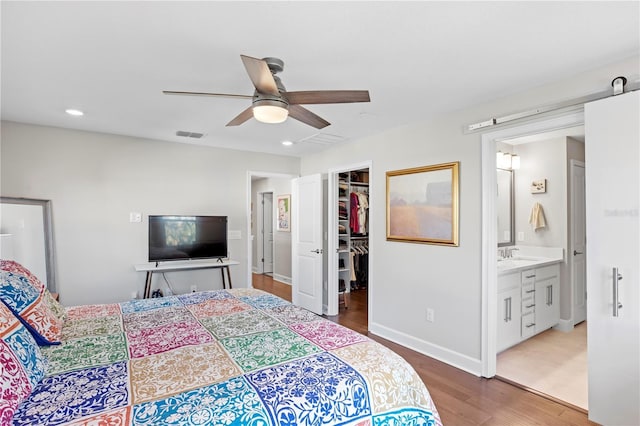 bedroom featuring a closet, visible vents, a spacious closet, a sink, and wood finished floors